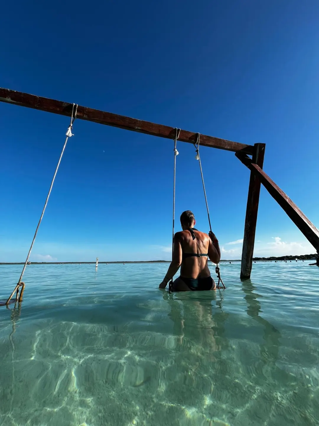 Voyageuse sur une balançoire dans une lagune turquoise